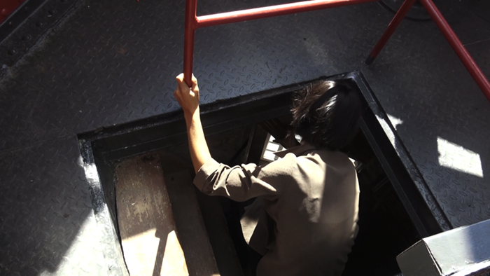 person looking into the depth of a lighthouse on top through trap door