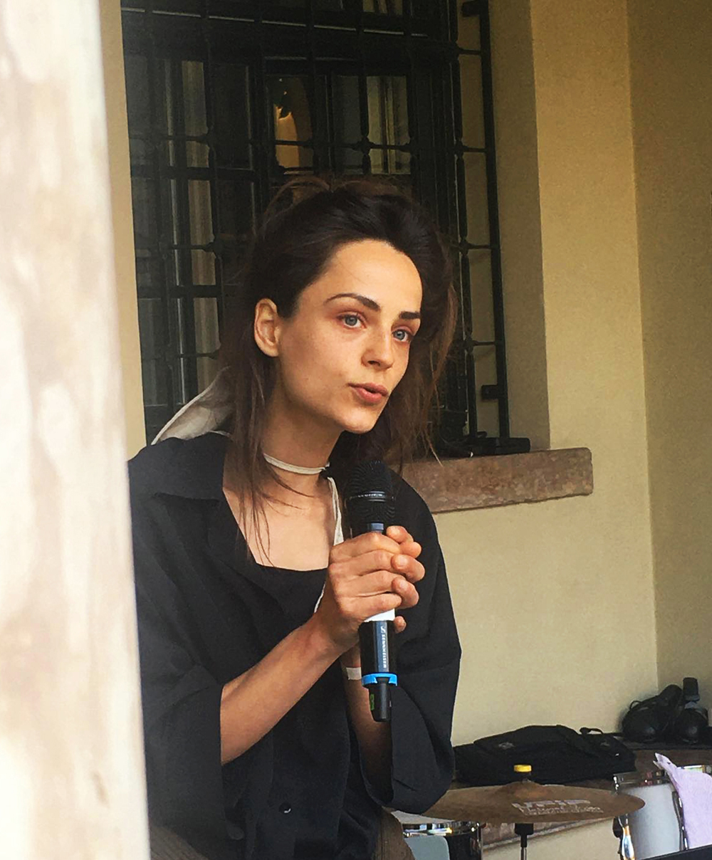 performer speaking into microphone in front of a facade, eyes looking up