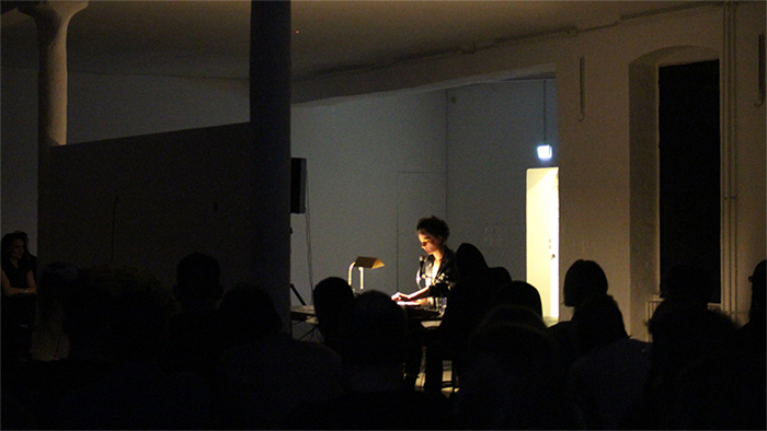 white wall in dark room, figure singing behind wall