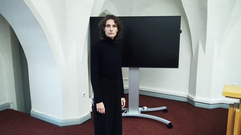 half total of woman facing camera in a courtroom, tv screen in background
