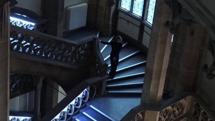 establishing shot of woman tumbling down neo-goethic staircase in laughter